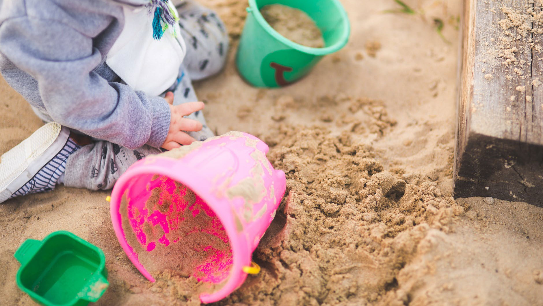 Child making sand castles in play pit