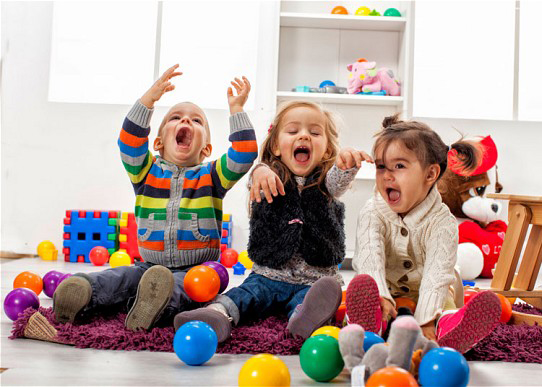 Young children sat playing with colourful balls on a purple rug