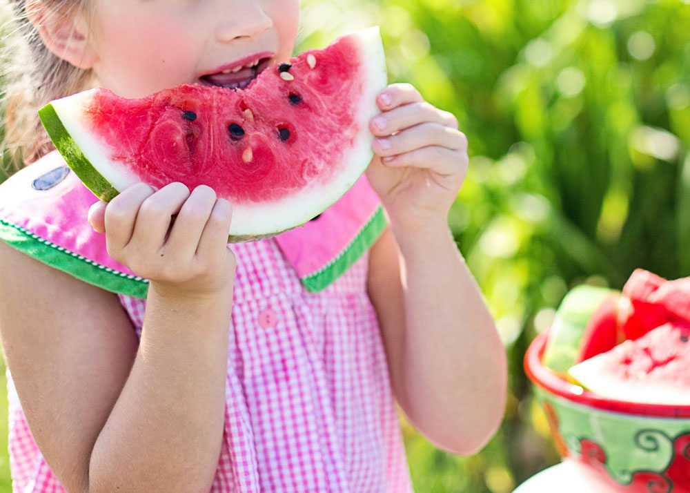 Young girl eating water melon outside in the sun