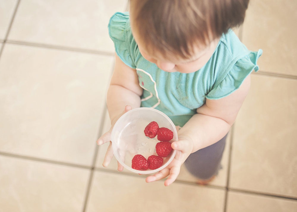 Young child holding a tub of strawberries