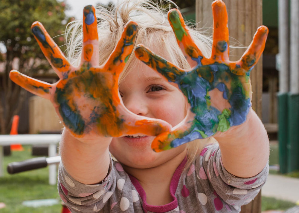 Little girl showing painted orange hands