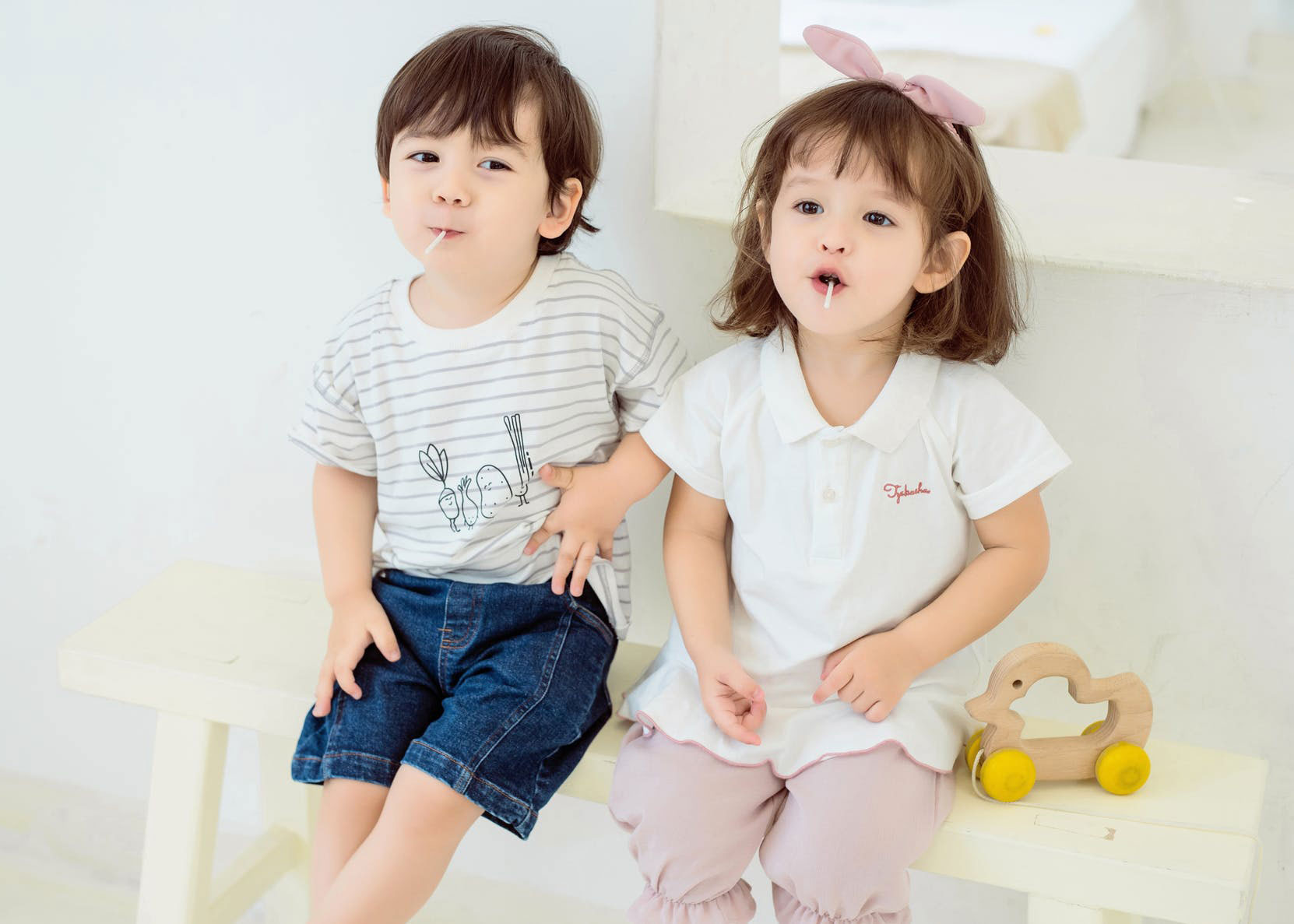 Young boy and girl with lolly pops in mouth sat down